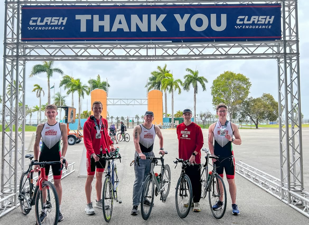 Five cyclists from the UNL Cycling Club pose in front of the finish line at a race