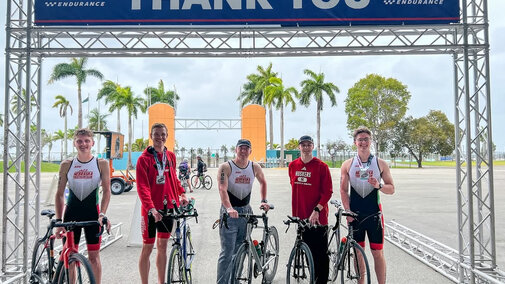 Five cyclists from the UNL Cycling Club pose in front of the finish line at a race