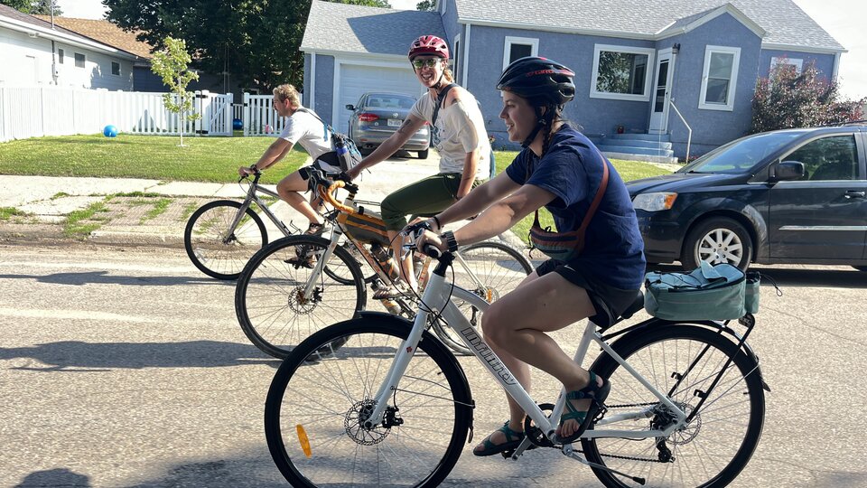 Three cyclists biking on a neighborhood street