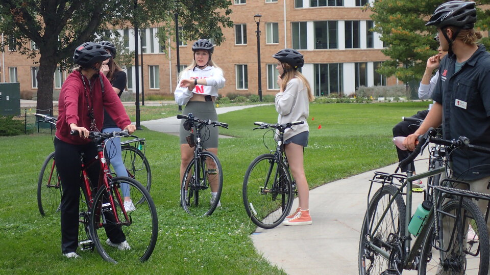 Cyclists on east campus turning to look at a cyclist speaking to them