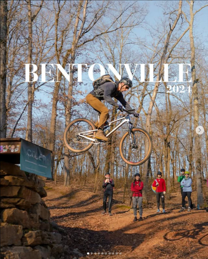 A mountain biker midair jumping off of a trail feature